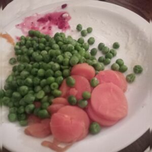 A plate full of peas and carrots.